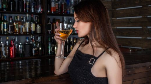 Kobieta pije drinka zrobionego przez barmana