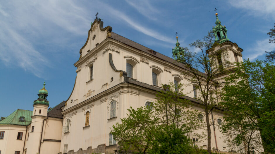 Na zdjęciu widać imponujący fragment katedry w Krakowie, która jest jednym z najważniejszych zabytków Polski. Detale architektoniczne, takie jak ostrołukowe okna, bogato zdobione rzeźby i maswerki, zapierają dech w piersiach i zachwycają swoim pięknem.