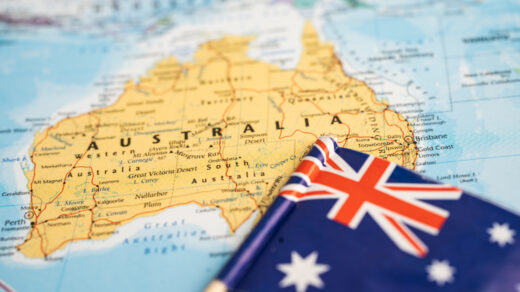 Na tym obrazku widzimy flagę Australii wplecioną w papierową mapę tego kraju. Flagę wyróżniają niebieskie pole z gwiazdami, symbolizujące położenie kraju na południowej półkuli, oraz czerwony krzyż pochodzący z flagi Wielkiej Brytanii, nawiązujący do historii kolonialnej Australii.