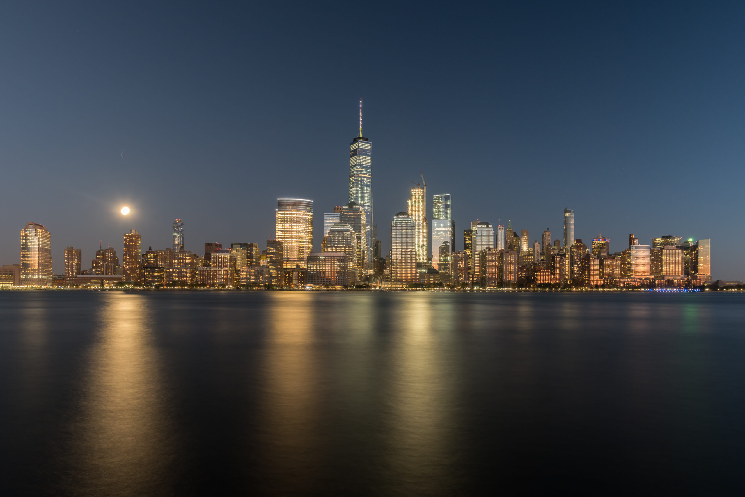Nocna panorama Nowego Jorku oczarowuje widzem swoim magicznym blaskiem, gdy wysokie wieżowce oświetlone tysiącami światełek wznoszą się ku niebu. Ta urzekająca sceneria przedstawia tętniące życiem miasto, gdzie neonowe reklamy i migotające okna tworzą niepowtarzalną atmosferę energii i niekończących się możliwości.