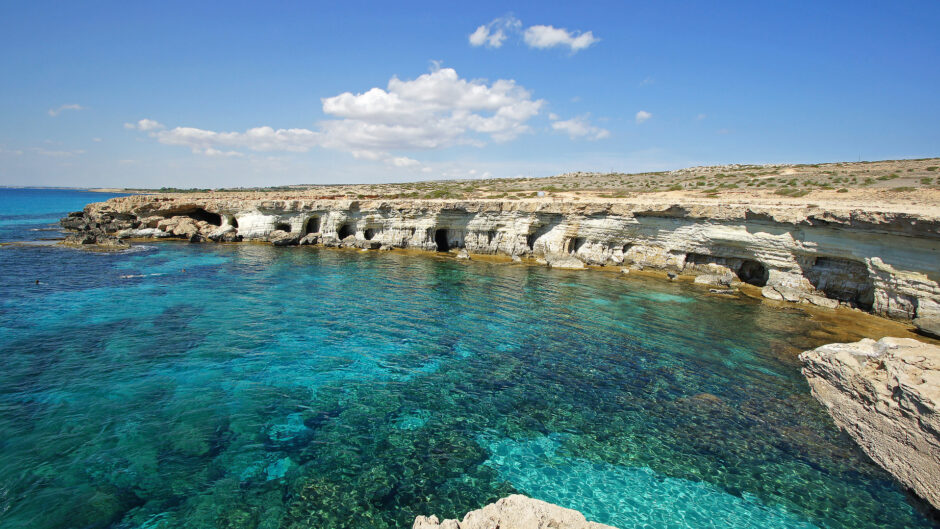 Wygeneruj opis obrazka, na którym znajduje się krajobraz cypru z plażą. niech ma trzy zdania.