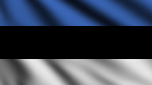 Na zdjęciu widać flagę Estonii, która składa się z trzech poziomych pasów - górnego niebieskiego, środkowego czarnego i dolnego białego. Flagę przewiewa delikatny wiaterek, co nadaje zdjęciu lekkości i ruchu. Zdjęcie to może być użyte w artykule lub na stronie internetowej o Estonii, aby zobrazować symbol narodowy tego kraju oraz jego historię i kulturę