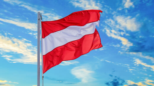 Flaga Austrii unosząca się na tle błękitnego nieba