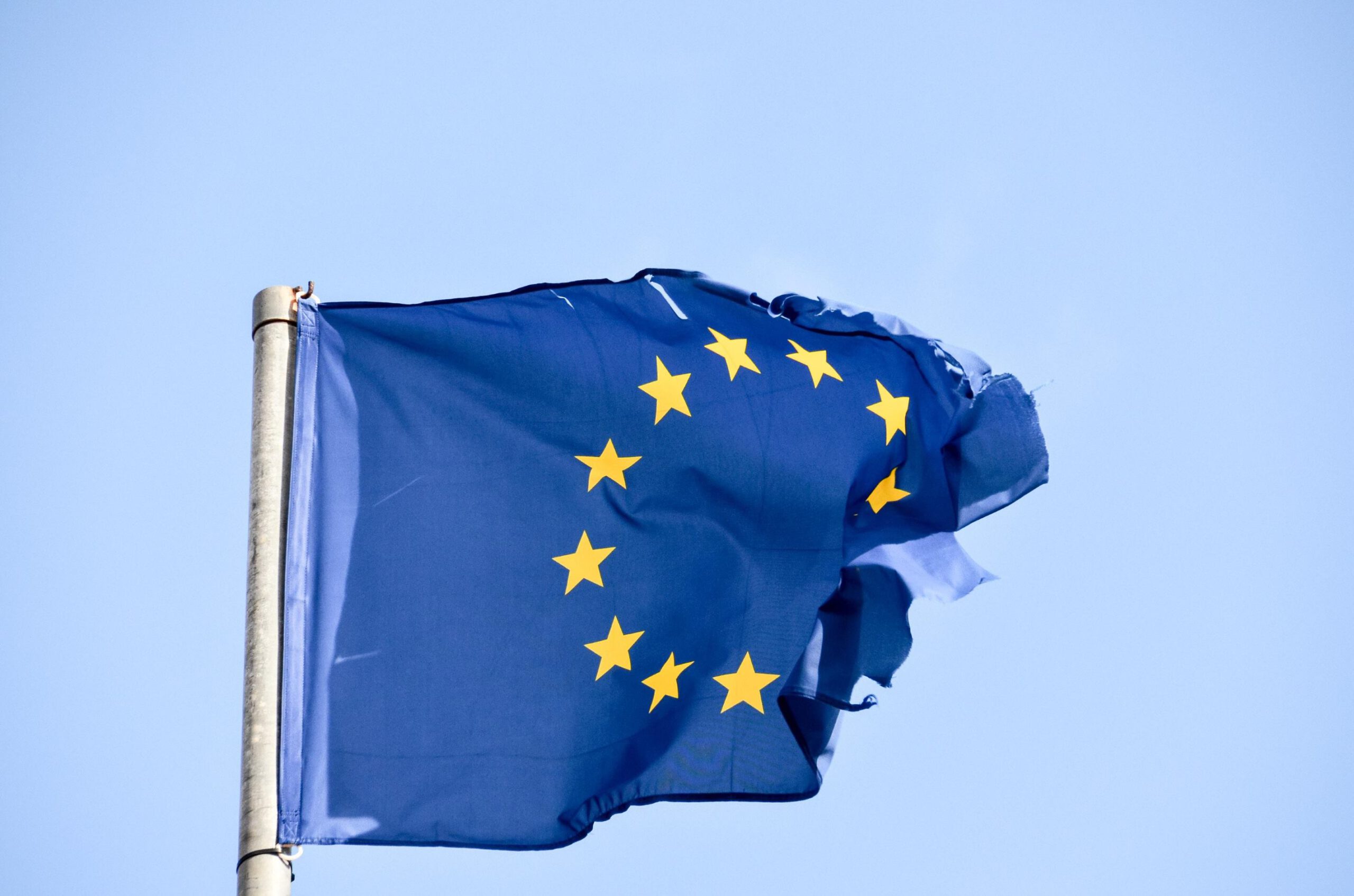 Flaga Unii Europejskiej, powiewająca dumnie na wietrze na tle niebieskiego nieba