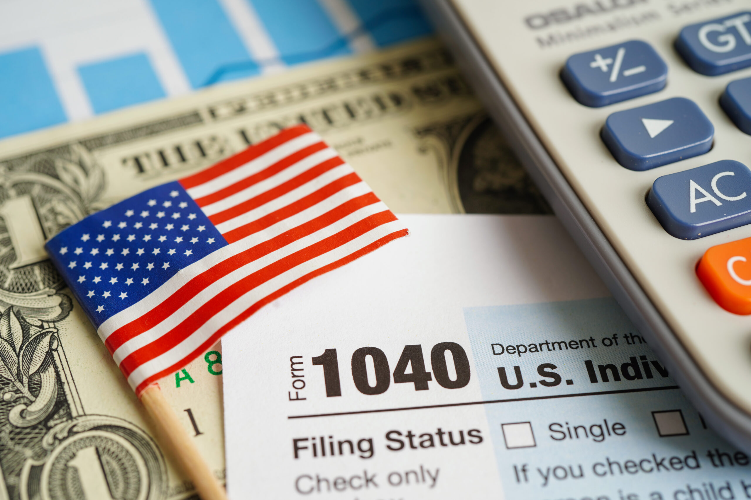 Flaga Stanów Zjednoczonych, kalkulator i banknoty, tworzące symboliczną reprezentację dochodu narodowego USA