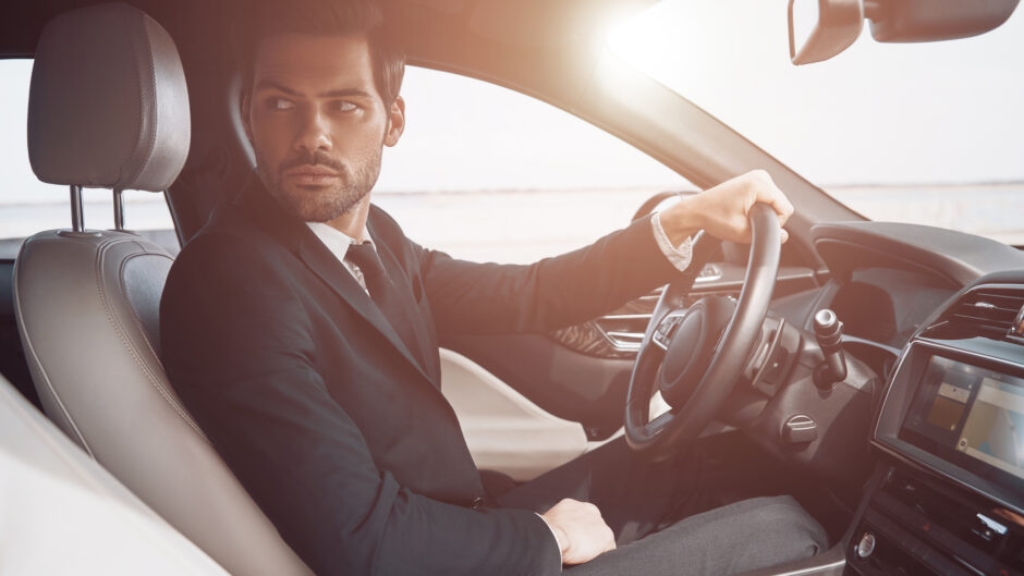Elegancki mężczyzna w garniturze za kierownicą samochodu