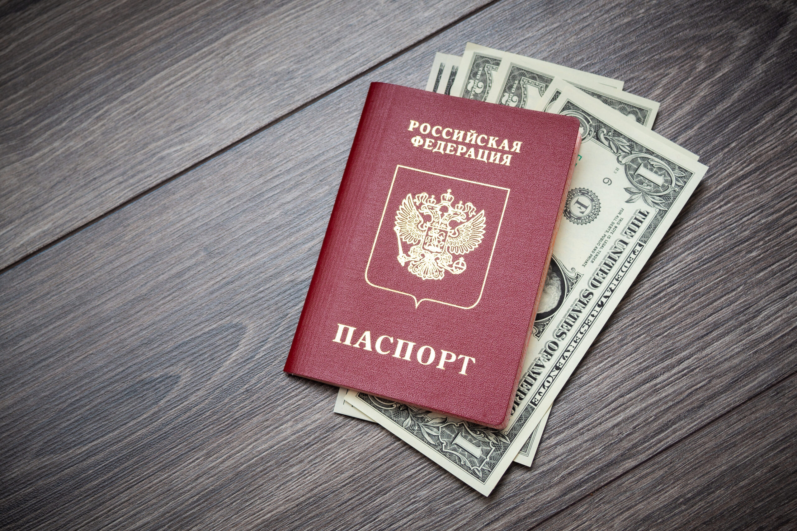 Rosyjski paszport z włożonymi w niego banknotami na drewnianym blacie