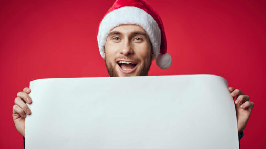 Uśmiechnięty mężczyzna w bożonarodzeniowej czapce, trzymający biały plakat