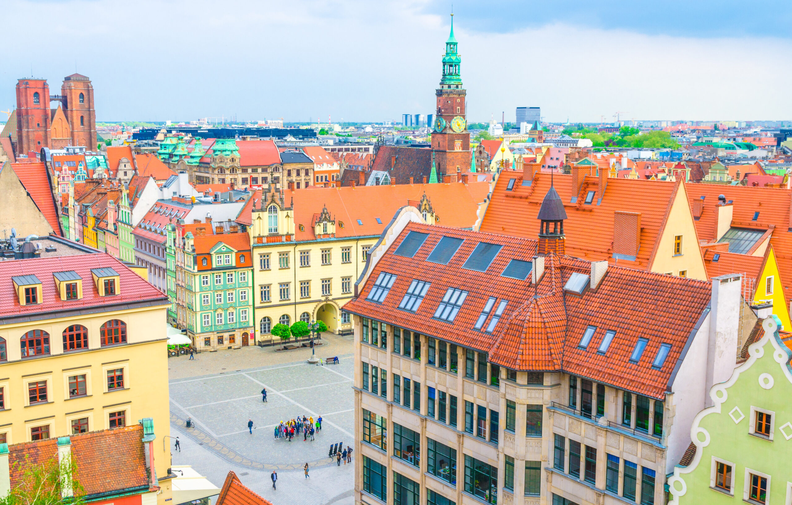 Na zdjęciu widać urokliwy i kolorowy Rynek we Wrocławiu, który jest jednym z najpiękniejszych rynków w Polsce. Ratusz oraz okalające go kamienice tworzą niepowtarzalny klimat miejsca, przyciągający turystów z całego świata. Zdjęcie podkreśla wartość turystyczną wrocławskiego rynku, który jest nie tylko pięknym zabytkiem, ale także centrum życia kulturalnego i rozrywkowego miasta.