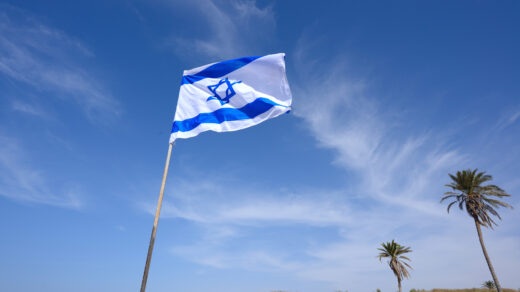 Flaga Izraela, składającą się z dwóch poziomych pasów - niebieskiego i białego - oraz złotego Gwiazdy Dawida w środku, powiewająca na wietrze