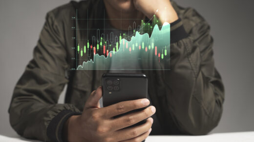 Mężczyzna skupiony na inwestowaniu w akcje, który analizuje wykresy i podejmuje strategiczne decyzje, trzymając telefon