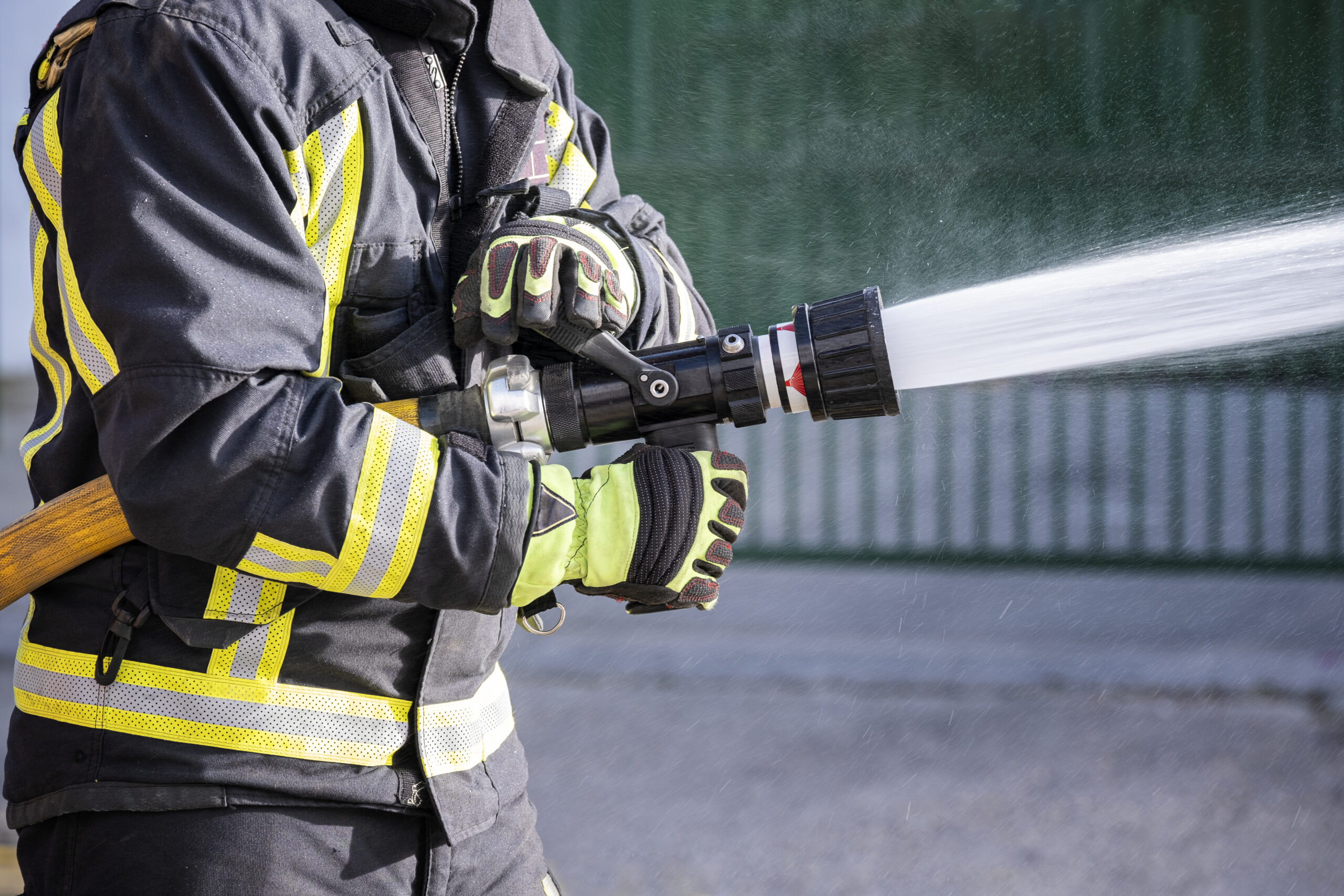 Strażak podczas akcji, który z determinacją gasi pożar, trzymając w rękach węża z wodą
