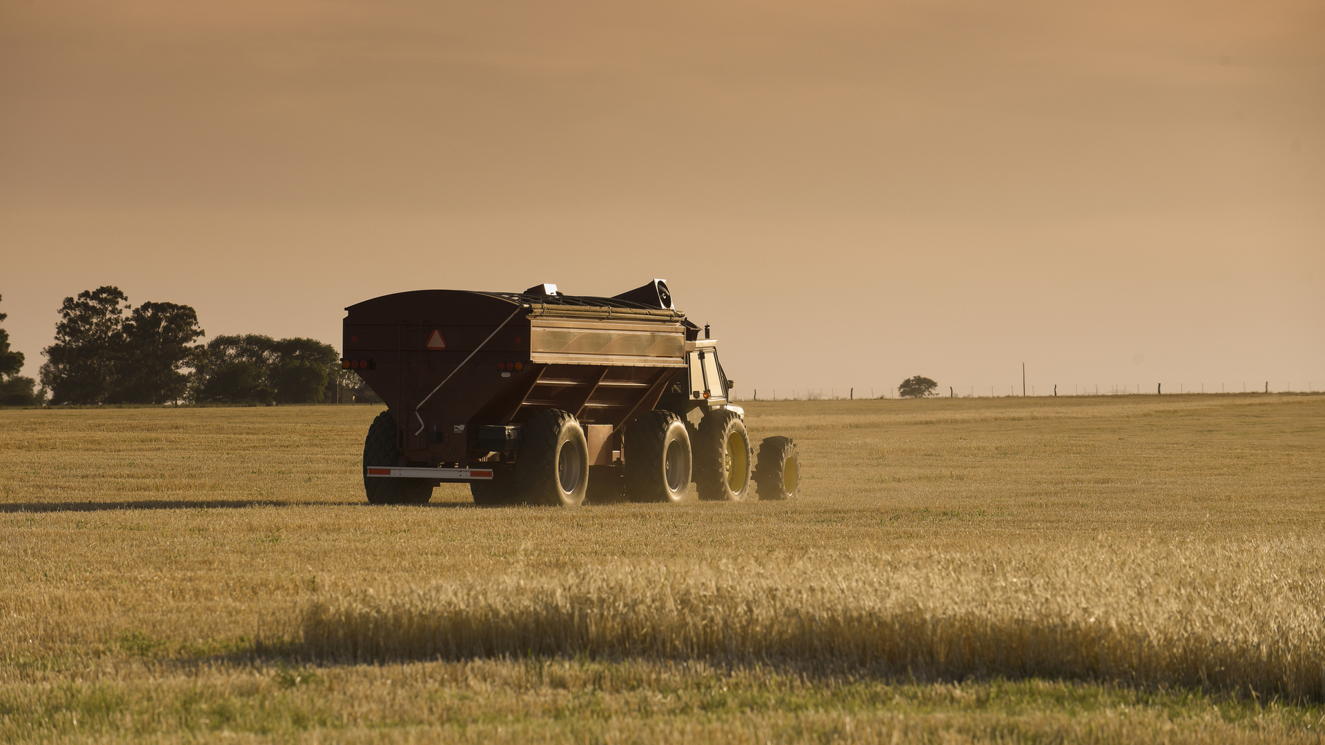 Traktor z przyczepą, które poruszają się po malowniczym polu na wsi