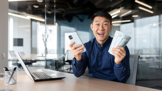 Product manager z banknotami w rękach przed biurkiem uśmiechający się do zdjęcia