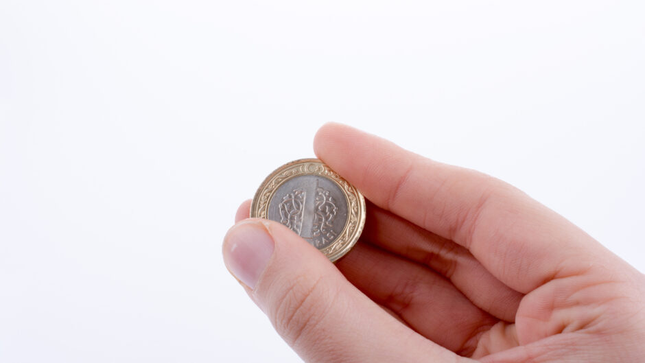 Moneta trzymana w dłoni, symbolizująca średnią krajową