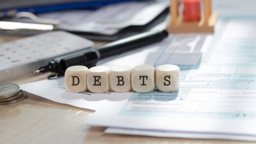 Kostki ułożone w słowo "debts", które symbolizuje dług publiczny